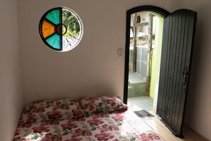 Ein Schlafzimmer mit einem Bett, einem Rundfenster und einer Tür, die nach draußen führt.