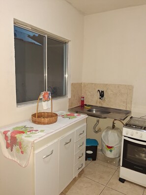 A kitchen with a window, a sink, a stove, and a cabinet.