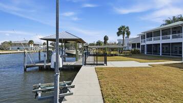 A waterfront property with a dock, a covered pavilion, and a large building with multiple windows.