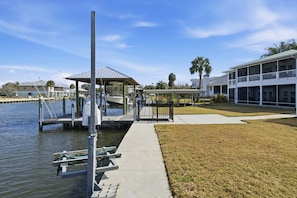 A waterfront property with a dock, a covered pavilion, and a large building with multiple windows.