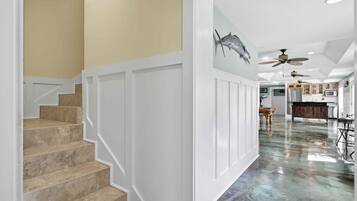 A staircase leading to a room with a polished floor, white walls, and ceiling fans.
