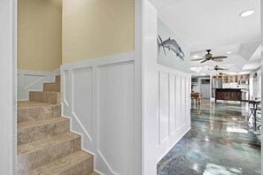 A staircase leading to a room with a polished floor, white walls, and ceiling fans. - Spacious 5-bedroom waterfront estate on the Crystal River with a pool and dock! (Crystal River)
