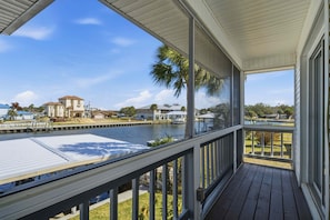 A covered balcony with a view of a water body and distant buildings.