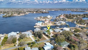 A residential area with houses near a body of water, docks, and a lighthouse in the distance.