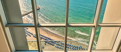 Um edifício alto com grandes janelas, oferecendo vista para o oceano e a praia.