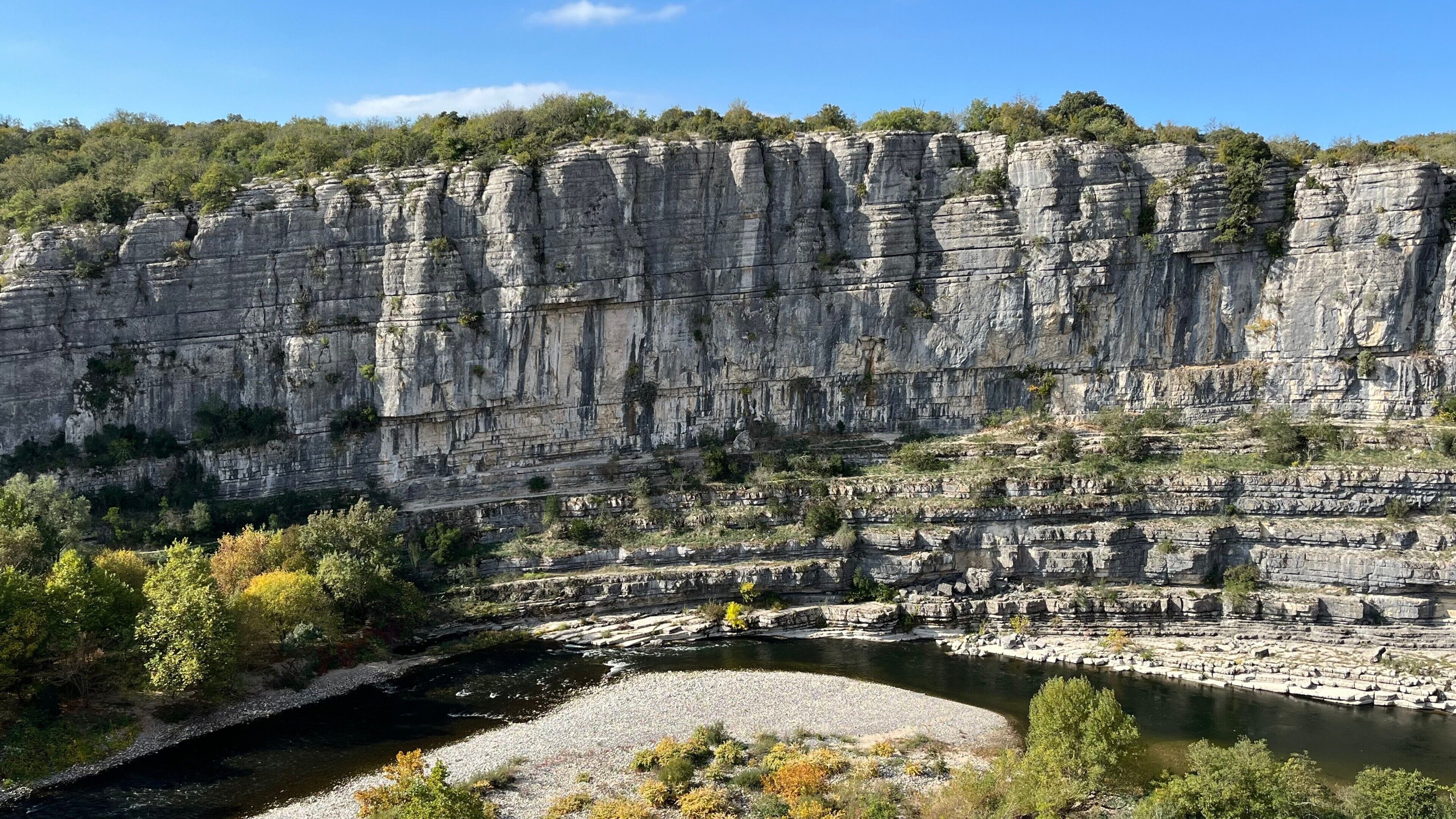 A natural rock formation with a river at its base.