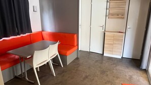 Ein Zimmer mit einem roten Sofa, einem kleinen Tisch, einem weißen Stuhl und einem Holzkasten.