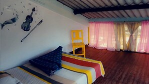 A room with a bed, a chair, a violin, and a wall with musical notes.