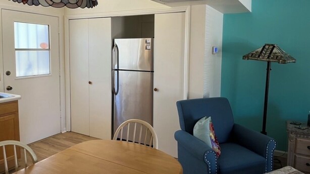 A kitchen with a refrigerator, a dining table with chairs, a blue armchair, and a floor lamp. - Charming apartment unit B ,  in beautiful Green Valley with cool AC breeze (Green Valley)