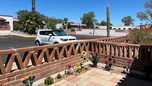 A parking lot with a white car, a brick wall with a decorative pattern, and various cacti and flowers. - Charming apartment unit B ,  in beautiful Green Valley with cool AC breeze (Green Valley)