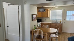 A compact kitchen with wooden cabinets, a dining table with chairs, and a pendant light. - Charming apartment unit B ,  in beautiful Green Valley with cool AC breeze (Green Valley)