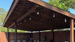 A covered outdoor patio with a grill and seating area.
