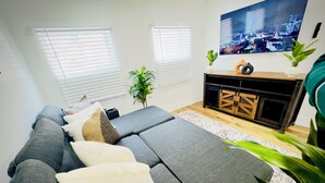 Un salon moderne avec un canapé d’angle, un téléviseur à écran plat et un meuble en bois.