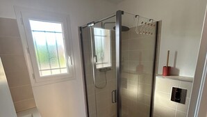 Een moderne badkamer met een douchecabine, toilet en wastafel.