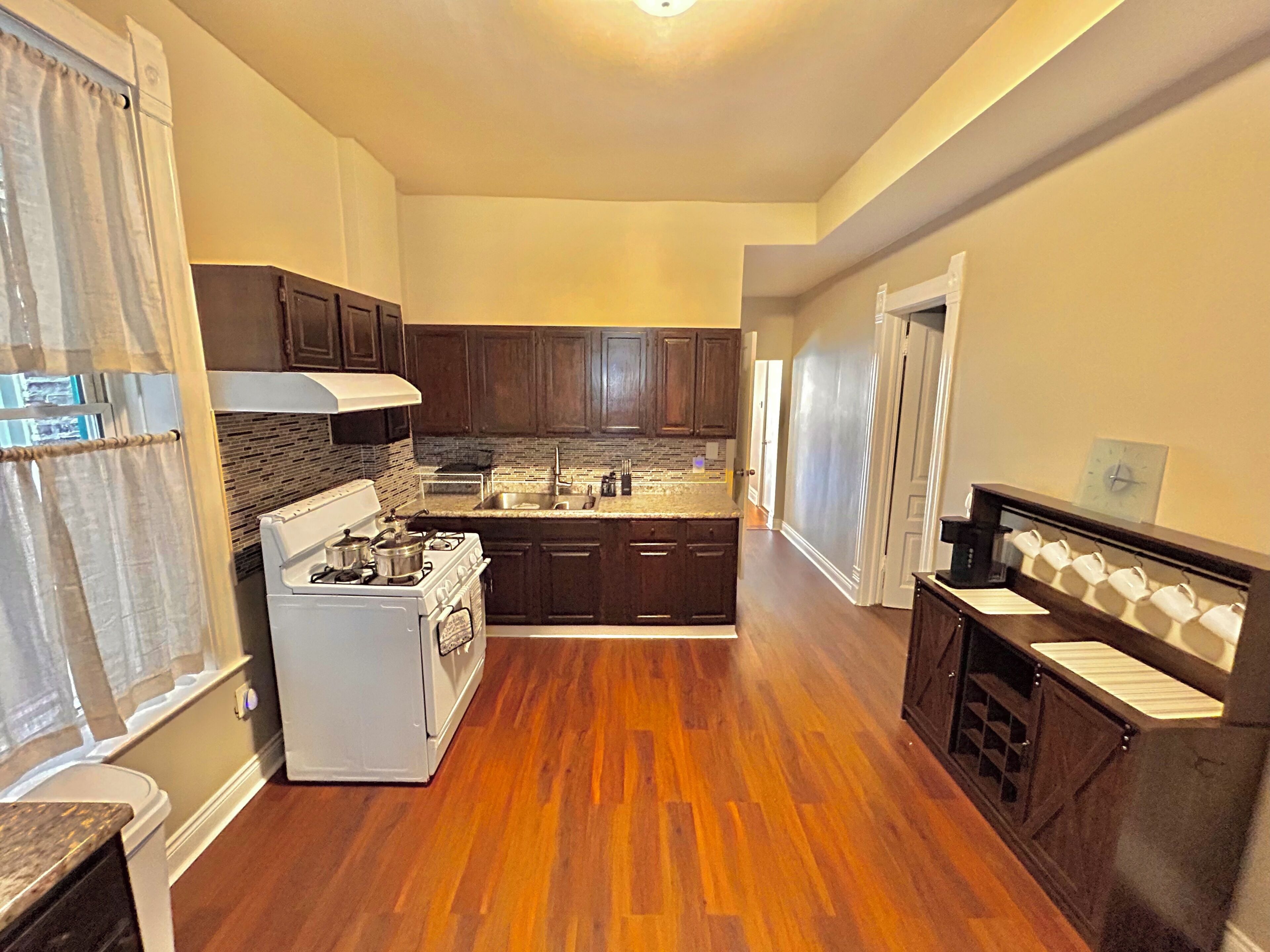 A kitchen with wooden cabinets, a white stove, a sink, and a countertop.