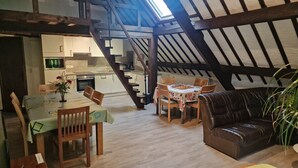 Un espacio habitable tipo loft con comedor, sofá, escalera y cocina.