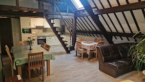 Ein Loft-Wohnraum mit Essbereich, einer Couch, einer Treppe und einer Küche.