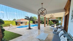 Un espacio al aire libre cubierto con piscina, sillas de descanso y un sofá.