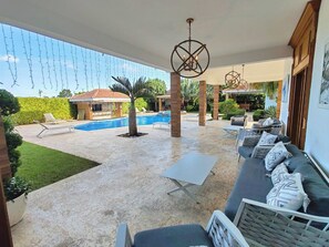 Ein überdachter Außenbereich mit Pool, Liegestühlen und einer Sitzecke.