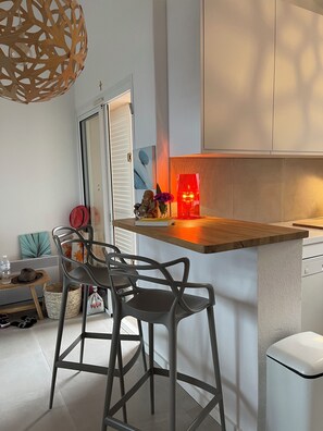 A modern kitchen with a wooden countertop, two bar stools, a small dining table, and a hanging light fixture. - Rental mini villa 180° sea view Palombaggia Porto Vecchio (Porto-Vecchio)