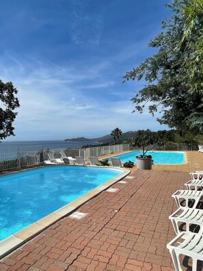 A swimming pool with a view of the ocean, surrounded by lounge chairs and a brick patio. - Rental mini villa 180° sea view Palombaggia Porto Vecchio (Porto-Vecchio)