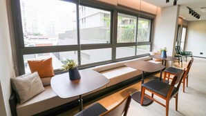 A modern interior with large windows, seating areas, and a staircase. - Studio Moderno GO Balkon Campo Belo - SP (São Paulo)