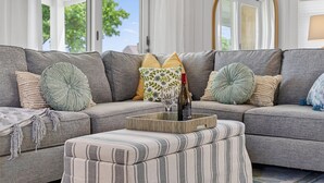 A sectional sofa with striped ottoman, a wine bottle, and glasses on a tray. - Steps To Peggotty Beach! Slps 10 + Dogs OK! (Scituate)
