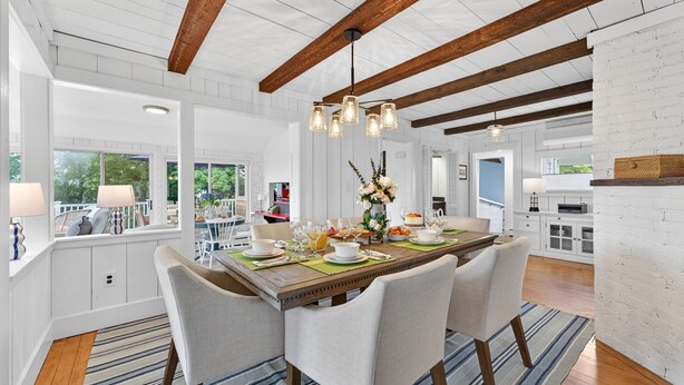 A dining area with a wooden table set for four, surrounded by chairs, under a hanging light fixture. - Steps To Peggotty Beach! Slps 10 + Dogs OK! (Scituate)