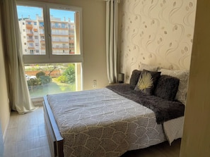 A bedroom with a bed, a sofa, a window, and a patterned wall. - Apartment near the airport, CAP 3000 and the beaches (Saint-Laurent-du-Var)
