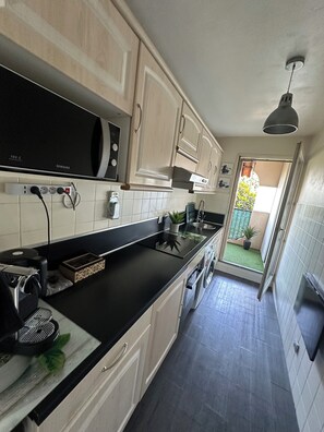 A modern kitchen with a black countertop, white cabinets, and a visible microwave. - Apartment near the airport, CAP 3000 and the beaches (Saint-Laurent-du-Var)