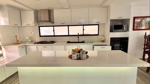 A modern kitchen with a central island, white cabinetry, and a large window. - Village of Prague. Country house with swimming pool. (Pasto)