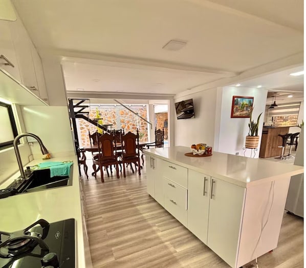 A modern kitchen with white cabinetry, a dining area with wooden chairs, and a kitchen island.