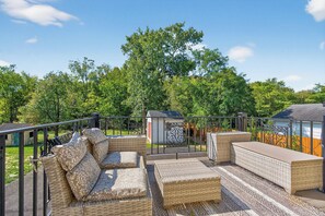 A patio with wicker furniture, a small shed, and a metal railing.