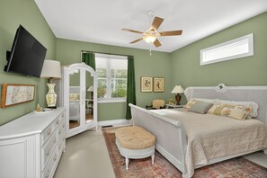 A bedroom with a bed, a vanity, a mirror, a ceiling fan, and a window with blinds.