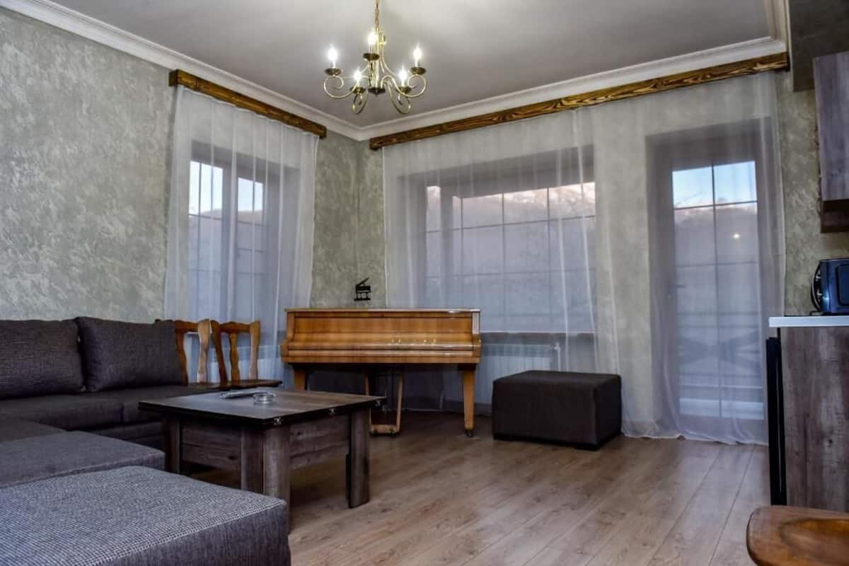 A living room with a piano, a sofa, a coffee table, and a television.