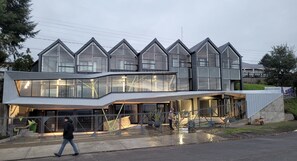 Ein modernes Gebäude mit einem einzigartigen architektonischen Design, das durch mehrere Satteldächer und große Fenster gekennzeichnet ist.