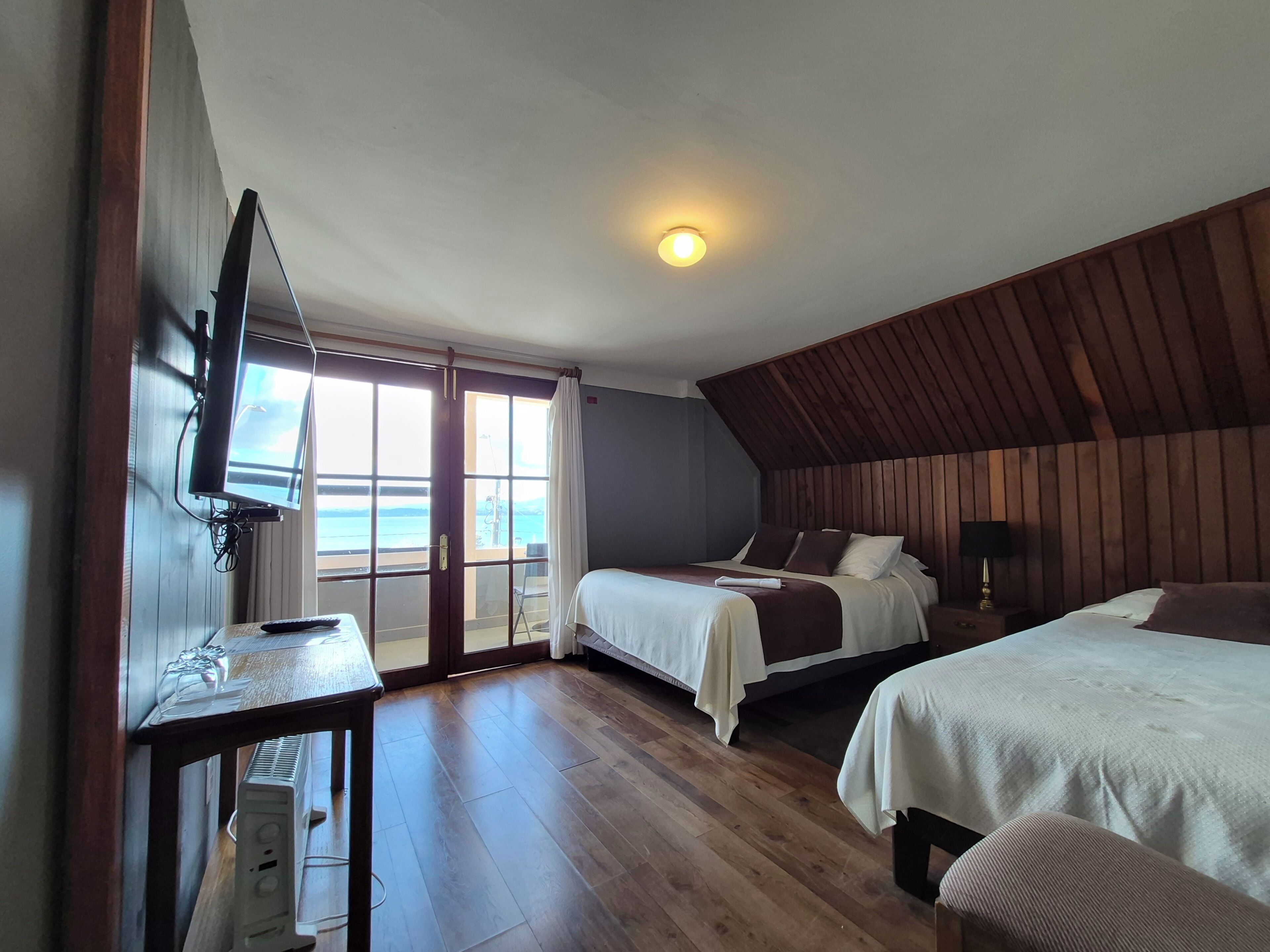 Ein Zimmer mit einem Bett, einem Schreibtisch mit Computer, einem Fernseher und Meerblick.