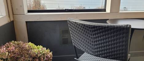 Una silla de mimbre cerca de una ventana con vista a un cuerpo de agua y montañas.