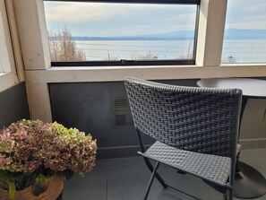 A wicker chair near a window with a view of a body of water and mountains. - Hotel Hosteria Entre Lagos (Puyehue)