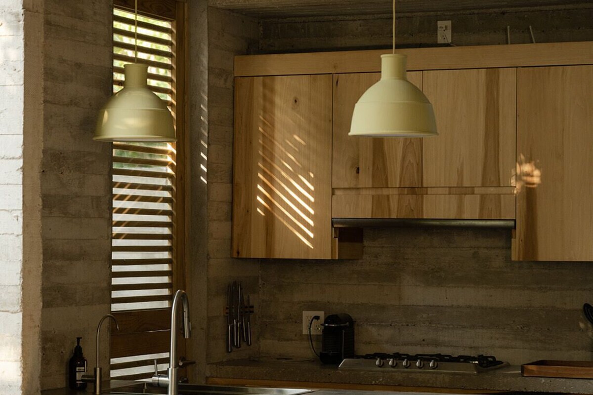 Una cocina moderna con armarios de madera, una barra con taburetes e iluminación colgante.