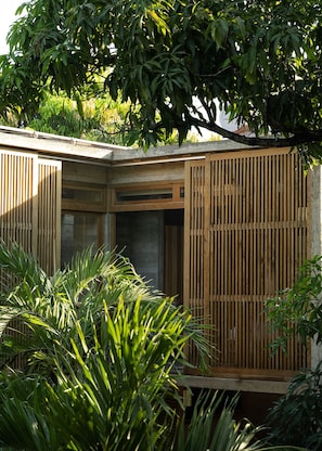 Un edificio moderno con fachada de madera, ventanas amplias y un árbol al fondo.