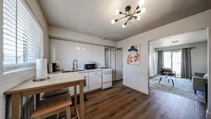 Eine moderne Küche mit weißen Schränken, einem Holztisch und einer auffälligen Deckenleuchte.