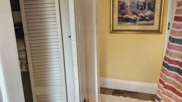 A hallway with a white door, a framed picture on the wall, and a striped curtain.