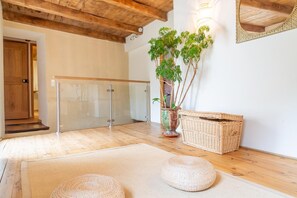 A room with a wooden ceiling, a glass door, a potted plant, a wicker basket, and a woven pouf. - EcoGîte Cévénola (sleeps 3) (MOLEZON)