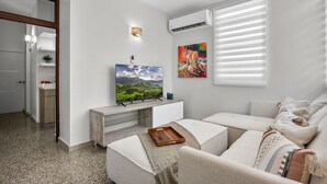 Ein modernes Wohnzimmer mit einem Flachbildfernseher, einer Kaffeestation und einem Sofa mit Tablett.