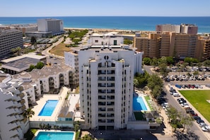 A high-rise hotel with a central courtyard, multiple swimming pools, and a view of the sea. - Apartment Tália with Pool by Centralgarve (Loulé)