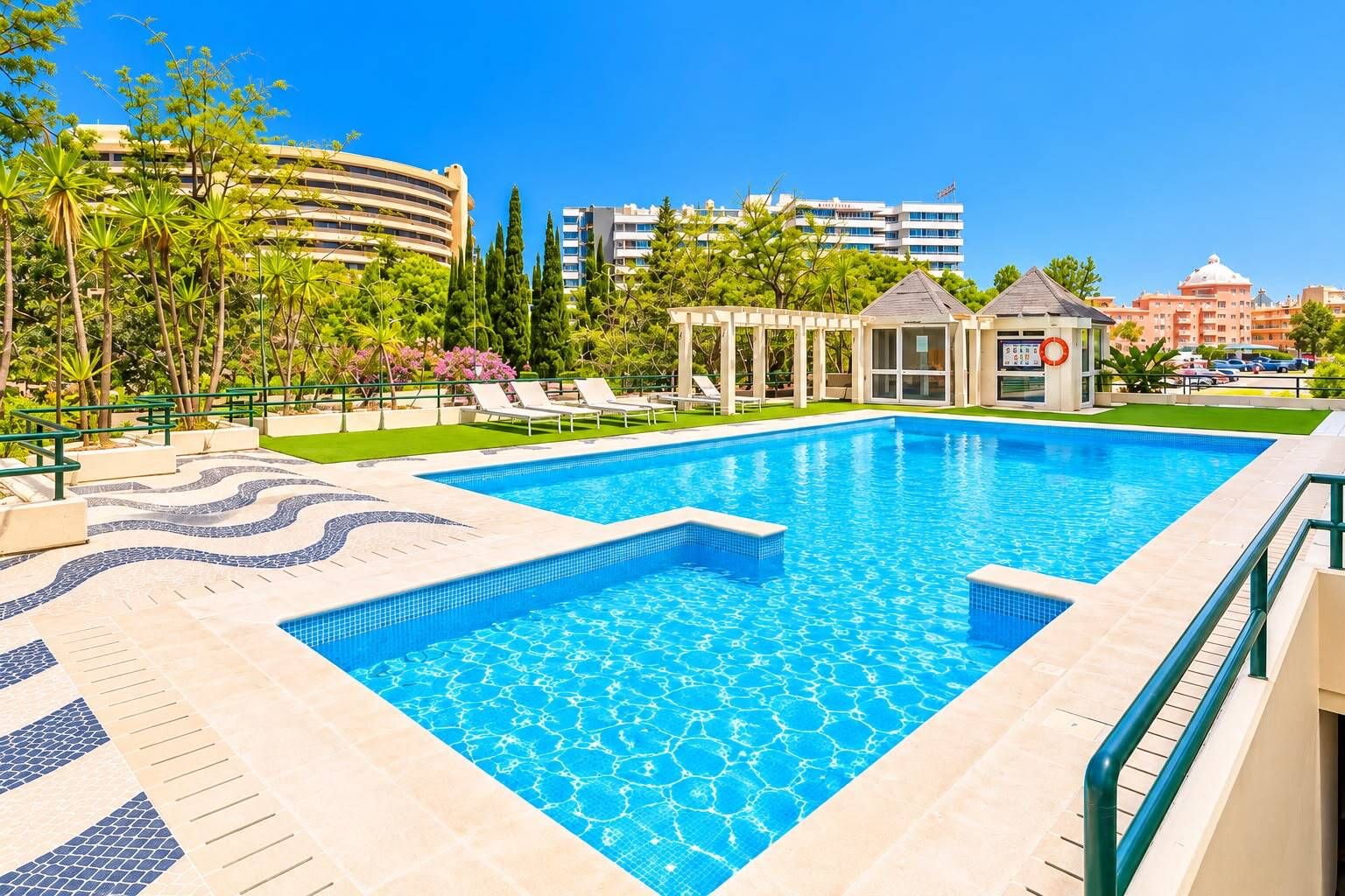 A swimming pool with lounge chairs and a gazebo, surrounded by greenery and buildings.