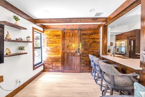 A modern kitchen with dark wooden cabinets, a large island with bar stools, and a sliding barn-style door.