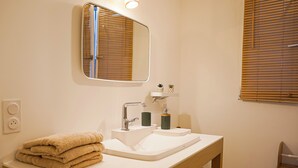 A bathroom with a sink, mirror, towel stack, and wooden chair. - La Casa de Miguel - Elegant cocoon 2 steps from the Palais des Papes (Avignon)