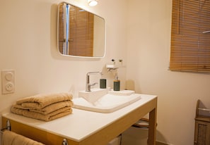A bathroom with a sink, mirror, towel stack, and wooden chair. - La Casa de Miguel - Elegant cocoon 2 steps from the Palais des Papes (Avignon)